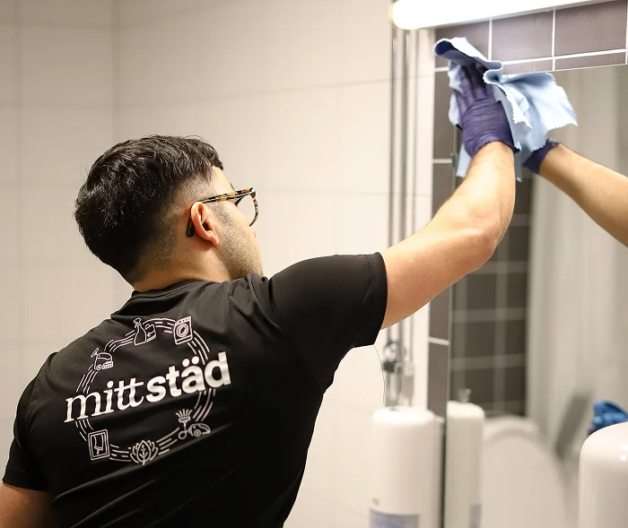 Person i Mittstäd-tröja putsar en spegel noggrant, som en del av företagets professionella städtjänster i Norrland. Person i Mittstäd-tröja putsar en spegel noggrant, som en del av företagets professionella städtjänster i Norrland.